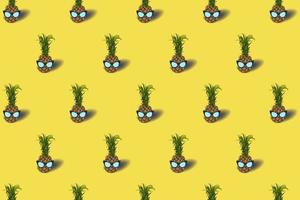 Pattern with pineapple fruit in a sunglasses - on an pastel yellow background. Black colored glasses. Summer concept - stylish vacation, juicy exotic and tropical fruit. Vector illustration.