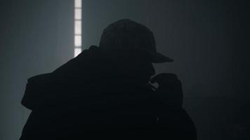mann sitzt auf dem bett in einem dunklen, verrauchten zimmer und raucht eine zigarette video