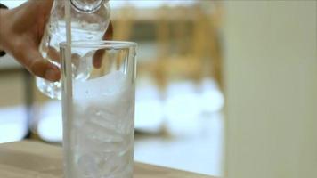 Video de 4k con enfoque selectivo al vaso lleno de hielo mientras se vierte agua