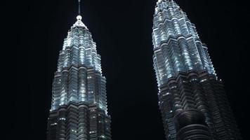 vista de ángulo bajo hasta las torres gemelas petronas financieras de gran altura rascacielos alto moderno edificio de diseño de gafas contra el cielo nocturno video