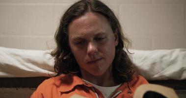 Prisoner, Handsome Man In Prison With Long Hair Sits In Cell Reading Bible video
