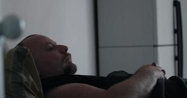 homme avec barbe dormant sur son lit et se réveillant, ouvrant les yeux video