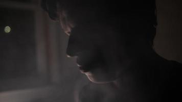 giovane uomo, adolescente ragazzo medita con chiuso occhi nel fumoso, buio camera video