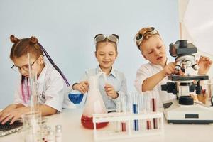 Test tubes with colorful liquid. Children in white coats plays a scientists in lab by using equipment photo