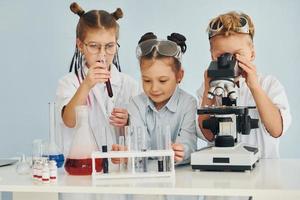 Test tubes with colorful liquid. Children in white coats plays a scientists in lab by using equipment photo