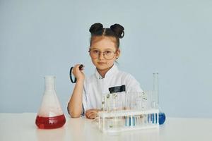 trabaja con tubos de ensayo. niñita con abrigo jugando a un científico en el laboratorio usando equipo foto