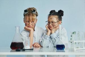 chica con chico trabajando juntos. los niños con batas blancas juegan a los científicos en el laboratorio usando equipos foto