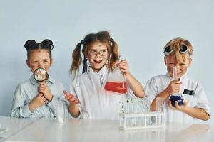 Happy friends smiling. Children in white coats plays a scientists in lab by using equipment photo