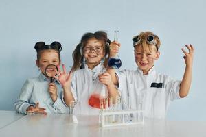 Happy friends smiling. Children in white coats plays a scientists in lab by using equipment photo