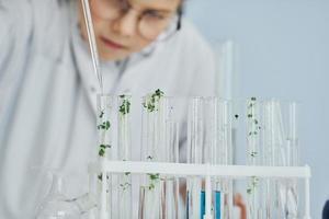 Works with test tubes. Little girl in coat playing a scientist in lab by using equipment photo