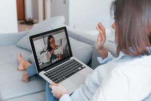 dos mujeres jóvenes tienen una conversación en línea usando una tableta foto