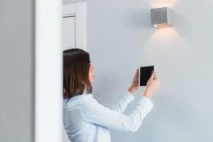 Switching the lighting. Young woman is indoors in smart house room at daytime photo