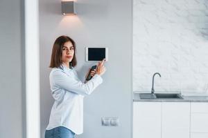 Controlling house by one touch. Young woman is indoors in smart house room at daytime photo