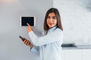 Controlling house by one touch. Young woman is indoors in smart house room at daytime photo