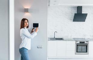 Controlling house by one touch. Young woman is indoors in smart house room at daytime photo