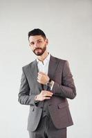 Posing for a camera against white background. Young stylish businessman in suit indoors photo