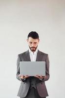With laptop in hands. Young stylish businessman in suit indoors. Conception of success photo