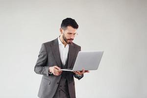 con la computadora portátil en las manos. joven y elegante hombre de negocios con traje en el interior. concepción del éxito foto