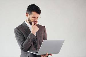 With laptop in hands. Young stylish businessman in suit indoors. Conception of success photo