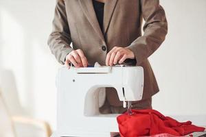 Seamstress working in the office. Young woman in formal clothes is indoors. Conception of style photo