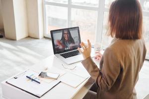 Video call with another girl. Young woman in formal clothes is indoors. Conception of style photo