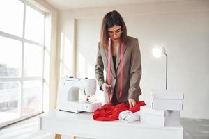 Seamstress working in the office. Young woman in formal clothes is indoors. Conception of style photo