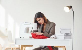 Seamstress working in the office. Young woman in formal clothes is indoors. Conception of style photo