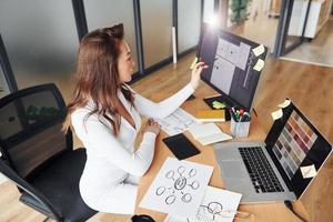 Using laptop. Young adult woman in formal clothes is indoors in the office photo