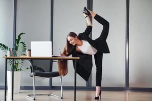 With laptop. Young adult woman in formal clothes is indoors in the office photo