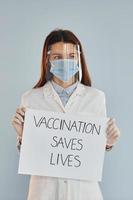 Vaccination saves lives banner. Young female doctor in white coat photo