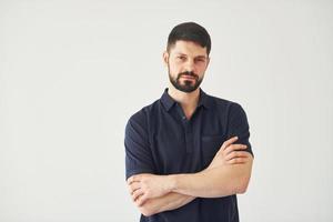 hombre serio en camisa de pie en el interior contra el fondo blanco foto