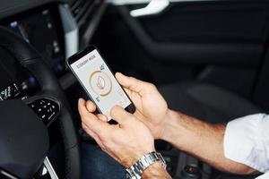 Close up view of man's hand that holds phone with labels and icons. Conception of remote control photo