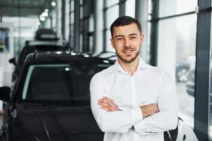 Young man in white shirt is indoors with modern new automobile photo