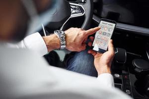 Young man in white shirt is sitting inside of a modern new automobile photo