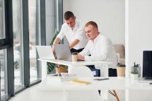 dos trabajadores de oficina masculinos con ropa formal trabajando juntos foto