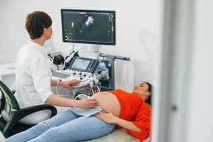 Ultrasound diagnostic. Pregnant woman is in the clinic in cabinet and have health check photo