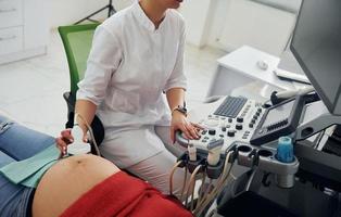 Ultrasound diagnostic. Pregnant woman is in the clinic in cabinet and have health check photo