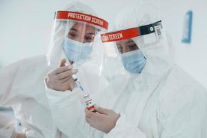 Female medical workers in protective uniform works on COVID-19 vaccine photo