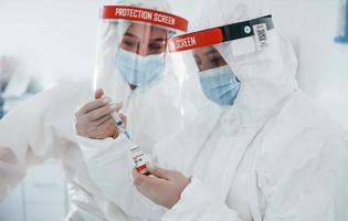 Female medical workers in protective uniform works on COVID-19 vaccine photo