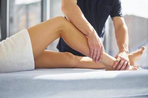 Guy does legs massage. Young woman is lying down when man serves her at spa photo