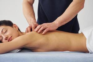 Young woman is lying down when man doing massage of her body at spa photo