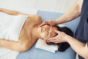 Top view. Young woman is lying down when man doing massage of her body at spa photo