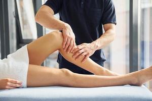 Guy does legs massage. Young woman is lying down when man serves her at spa photo