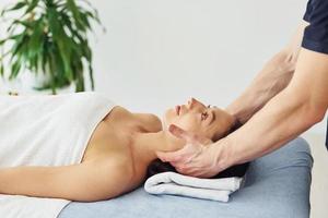 Head massage. Young woman is lying down when man doing procedure to her in spa photo