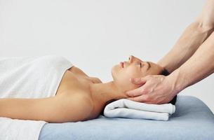 Head massage. Young woman is lying down when man doing procedure to her in spa photo