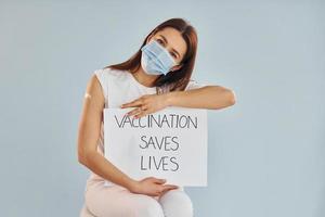 Young woman in mask is sits after vaccine injection indoors photo