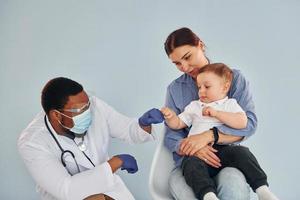 Mother with her little son is in the hospital with african american doctor photo