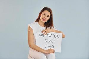 Young woman in mask is sits after vaccine injection indoors photo