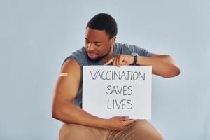 Vaccination saves lives banner. Young african american man after vaccine injection photo