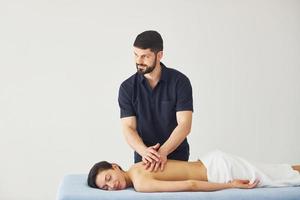 Young woman is lying down when man doing massage of her back at spa photo